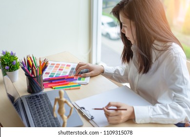 Young Asian Woman Designer Working With Color Samples For Selection On Office Desk, Architects Choosing Color Samples For Design Project,creative Graphic Design Working Desktop.