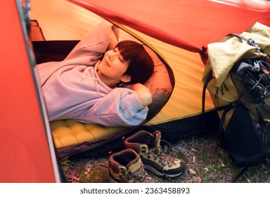 Young Asian woman is doing solo camping. She is lying in a tent. - Powered by Shutterstock