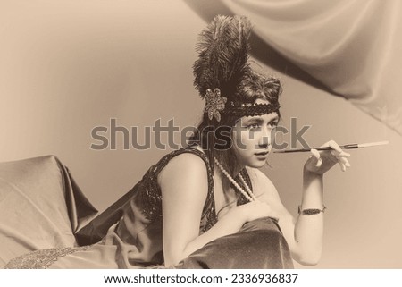 Young asian woman dressed in a flapper outfit in a vintage style photo smoking a cigarette in a long filter.