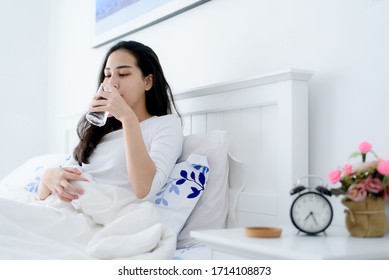 Young Asian Woman Drink Water From A Glass After Wake Up In The Morning In A Bedroom.