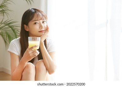 A Young Asian Woman Drinking A Fruit Juice