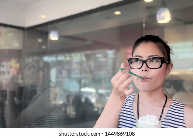 A Young Asian Woman Drinking Green Tea Frappe.