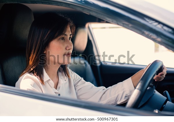 young asian woman driver driving a\
car,with hand handle\
 steering wheel,vintage\
effect