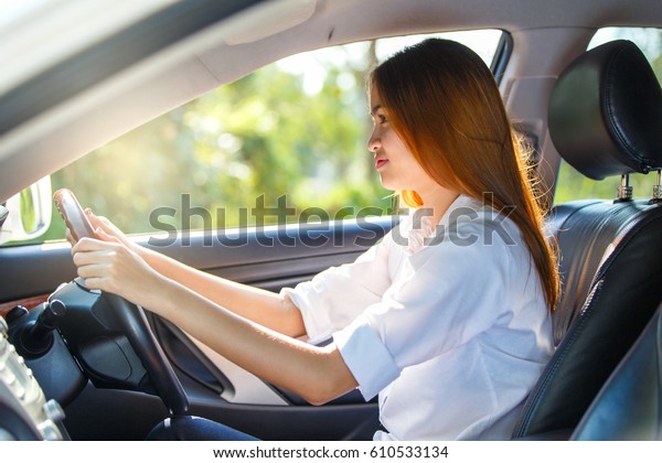 Young asian woman driver driving a car on the\
road in countryside