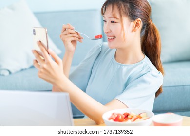 Young Asian Woman Eating Breakfast And Selfie In Her Living Room