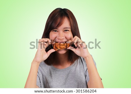 Young Asian woman eating chicken on green background