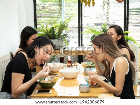 Young Asian Woman eats spicy hot tomyum noodle soup and hanging on chopstick to mouth with sweat delicious enjoy eating together