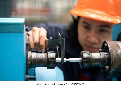 young asian woman engineer using vernier for measure the test piece on the machine