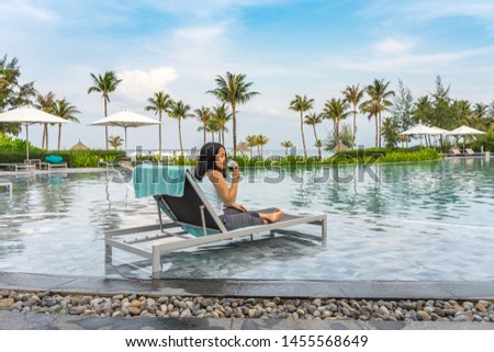 Young Asian woman enjoy red wine at beautiful swimming pool