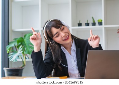 Young Asian Woman Enjoying Listening To Music Wearing Headphones Feeling Relax In Office Desk.