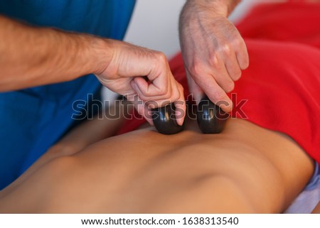 Young Asian woman enjoying the therapeutic effects of a traditional hot stone massage at luxury spa and wellness center.