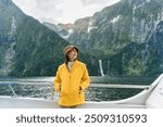 Young asian woman enjoying the view of Milford Sound during ferry cruise on vacation at Fjordland national park, New Zealand