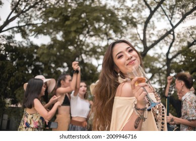 A young asian woman enjoys a boho themed party or festival outdoors with friends.