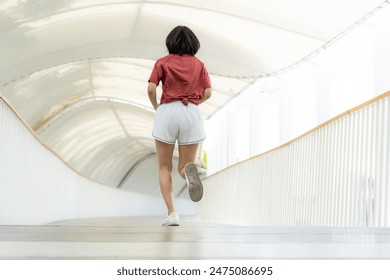 Young Asian woman exercising jogging outdoors in park. Smiling female runner in sports clothing running outside in urban city in the morning. Wellbeing healthy lifestyle person. Copy space. - Powered by Shutterstock