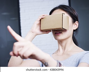 young asian woman experiencing virtual reality with cardboard VR glasses. - Powered by Shutterstock