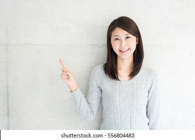 Young Asian Woman Explaining Against Concrete Wall