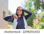 A young asian woman facepalms while checking her wristwatch. Late for a date, school or work.
