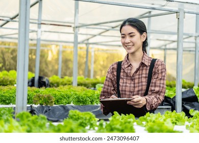 Young asian woman farmer or inspection of plant growth in greenhouse or sustainability in quality control, clipboard or notes on lettuce production or feedback on hydroponic agriculture system - Powered by Shutterstock