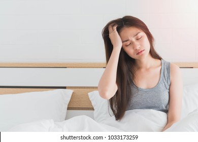 Young Asian Woman Feel Headaches And Discomfort On Bed In White Bedroom Morning.Concept Of Women's Health Care.