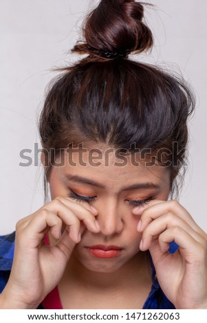 Young asian woman feeling hurt, itchy or irritate on her eyes afrer put contact lens into eyes. Girl crying tears on face, hands touching eyes isolated on white background.