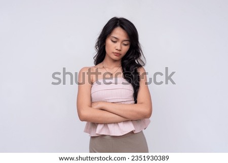 A young asian woman feels disappointed at herself. Looking downward looking sad. Ruminating on sad thoughts. Isolated on a white background.