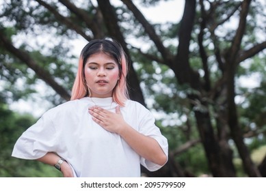 A young asian woman feels rapid, fluttering heartbeat on her chest. Possible cardiac problems, dyspnea or anxiety attack. - Shutterstock ID 2095799509