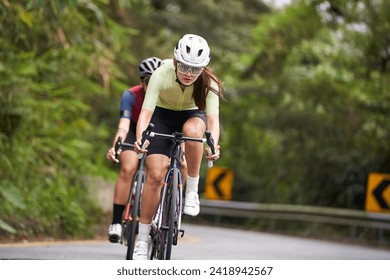 young asian woman female cyclist riding bicycle outdoors on rural road - Powered by Shutterstock