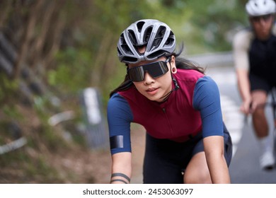 young asian woman female cyclist riding bicycle outdoors on rural road - Powered by Shutterstock