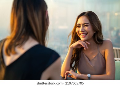 Young Asian Woman Friends Celebrating Dinner Party Meeting At Skyscraper Rooftop Restaurant Bar In Metropolis At Summer Sunset. Beautiful Girl Enjoy Outdoor Lifestyle Together On Holiday Vacation.