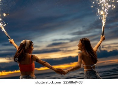 Young Asian woman friends dancing and playing sparklers firework together at tropical beach in summer night. Attractive girl enjoy and fun outdoor lifestyle travel nightlife party on holiday vacation. - Powered by Shutterstock