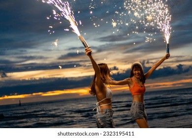 Young Asian woman friends playing sparklers firework together at tropical island beach at summer sunset. Attractive girl enjoy and fun outdoor lifestyle beach party on holiday travel vacation. - Powered by Shutterstock