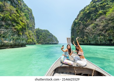 Young Asian woman friends using mobile phone taking selfie together while travel on boat passing island beach lagoon in sunny day. Happy female enjoy and fun outdoor lifestyle on summer vacation trip