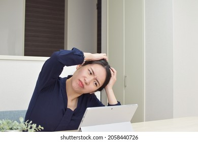 A young Asian woman gets depressed and holds her head during telework