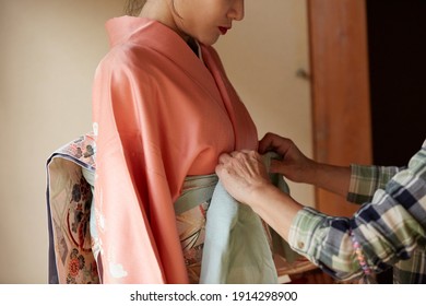 A Young Asian Woman Getting Dressed In A Kimono