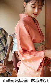 A Young Asian Woman Getting Dressed In A Kimono