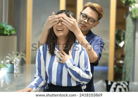 Young Asian woman, girlfriend happy, surprised, Asian man, boyfriend wearing glasses, blindfolded, happy couple playing and teasing each other in coffee shop