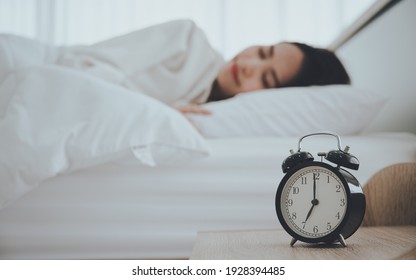 Young Asian Woman Happy Sleep At Morning In Bedroom. Closeup Of Alarm Clock On White Bed