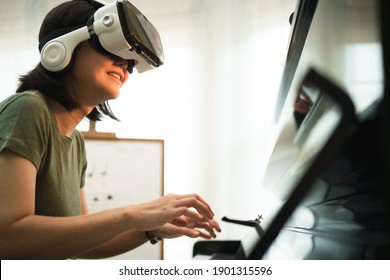 Young Asian Woman Have Fun With New Technology VR Headset By Playing Piano Music Lesson At Home, Virtual Reality Musical Online Learning Concept, Pianist Conduct Student From VR Technology. Metaverse.