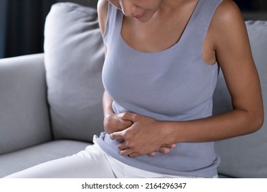 Young Asian Woman Having A Stomach Ache. Menstrual Period Cramp, Abdominal Pain, Food Poisoning. Health Care And Medical Concept.