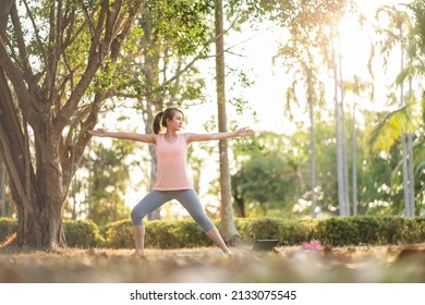 Young Asian Woman Healthy In Sportswear Workout Practice Yoga In Nature Park Outdoor Under Sunset. Healthy Lifestyle And Relaxation.