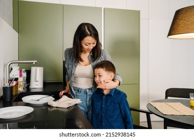 Young Asian Woman And Her Little Son Cleaning Dishes Together After Dinner In Kitchen