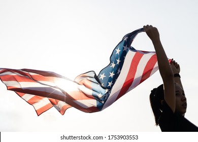 A Young asian woman holding American flag with sun flare. - Powered by Shutterstock