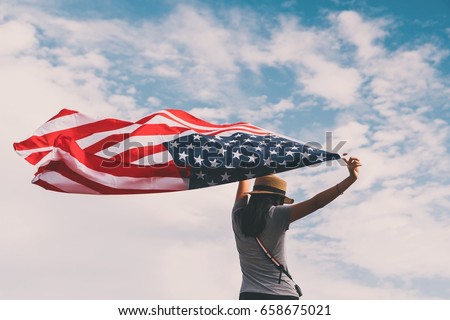 Young asian woman holding American flag on blue sky background