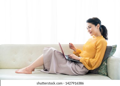 Young Asian Woman Holding A Credit Card And A Laptop.