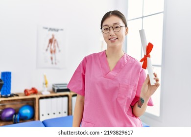 Young Asian Woman Holding Degree At Physiotherapy Clinic