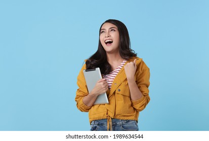 Young Asian Woman Holding Digital Tablet And Happy Laugh Isolated On Blue Background.