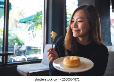 A Young Asian Woman Holding And Eating Donut