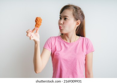 Young asian woman holding and eating fries chicken on white background - Shutterstock ID 2169309931