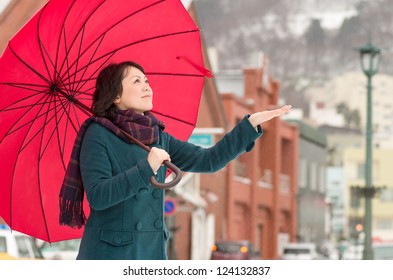 Young Asian Woman Holding Up Her Umbrella In Winter City