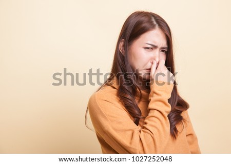 Young Asian woman  holding her nose because of a bad smell on beige background ストックフォト © 